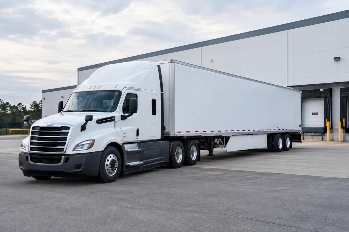 White tractor-trailer positioned at a distribution warehouse
